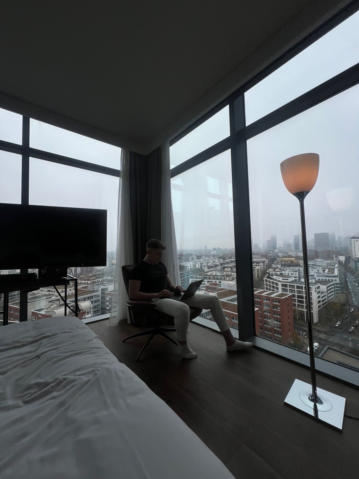 Kadir arbeitet mit dem Laptop vor einer Fensterfront mit Blick über die Stadt